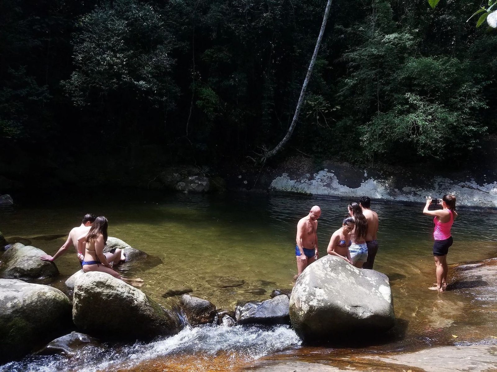 Visitantes em parada para banho em um rio de águas claras